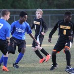 young boys playing soccer on a field.