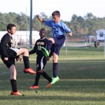 young boys playing soccer on a field.