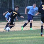 young boys playing soccer on a field.