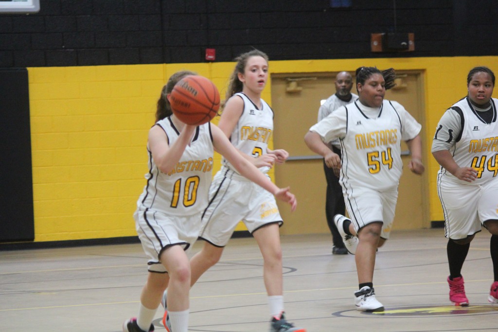 A group of young female basketball players in action during a game on the court.