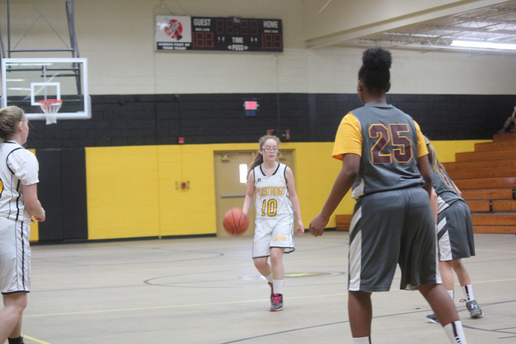 Young female basketball players compete in a game, dribbling and shooting on the court.