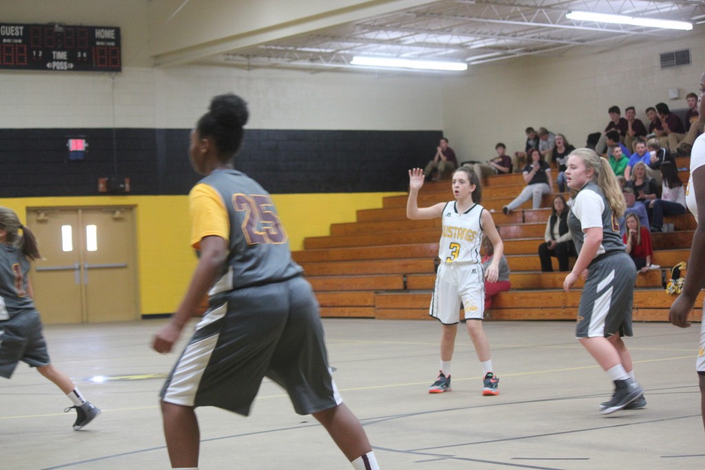 A group of female basketball players in action on the court in a gymnasium.