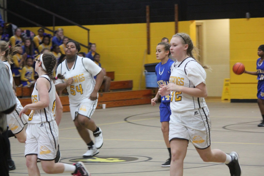 Young female basketball players sprinting down court during intense game.