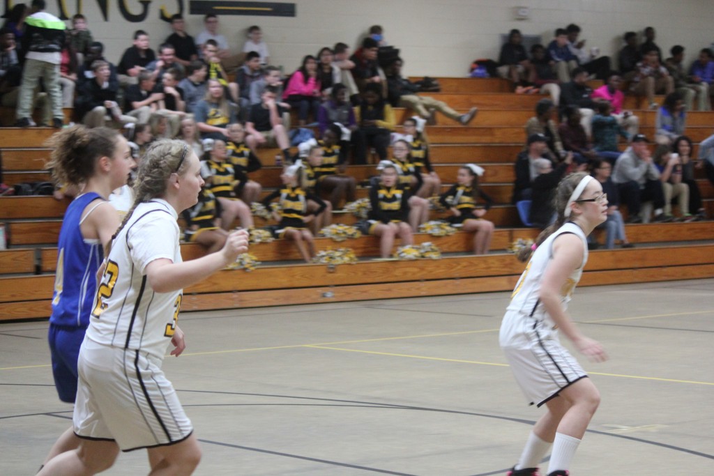 Young female basketball players dribbling and shooting on the court during a game.