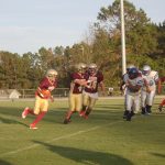 A group of athletes playing football on a grassy field.