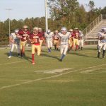 A group of athletes playing football on a grassy field.