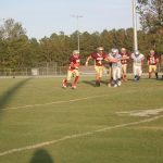 A group of athletes playing football on a grassy field.