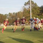 A group of athletes playing football on a grassy field.