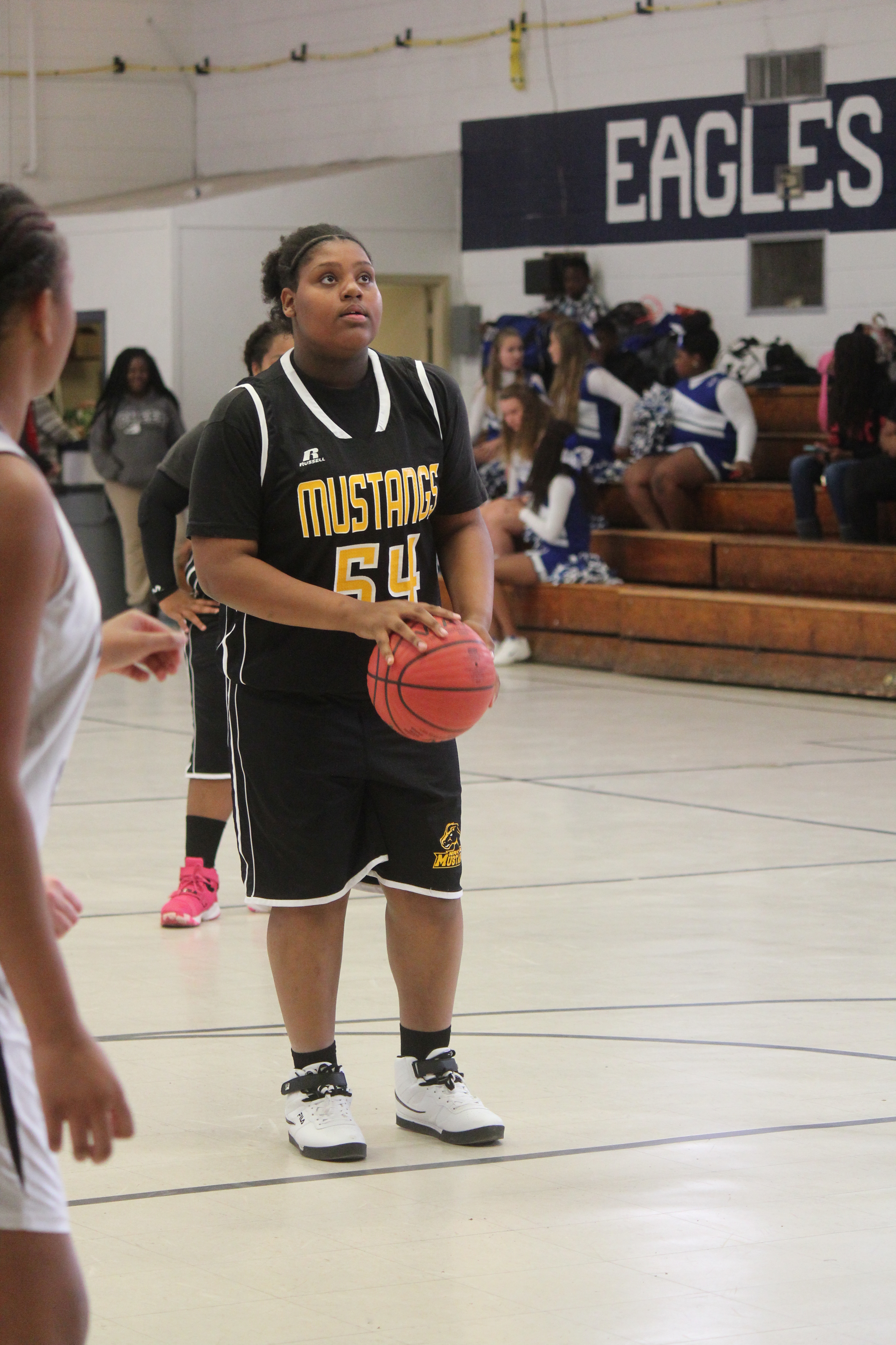 Young woman in black jersey holding basketball.