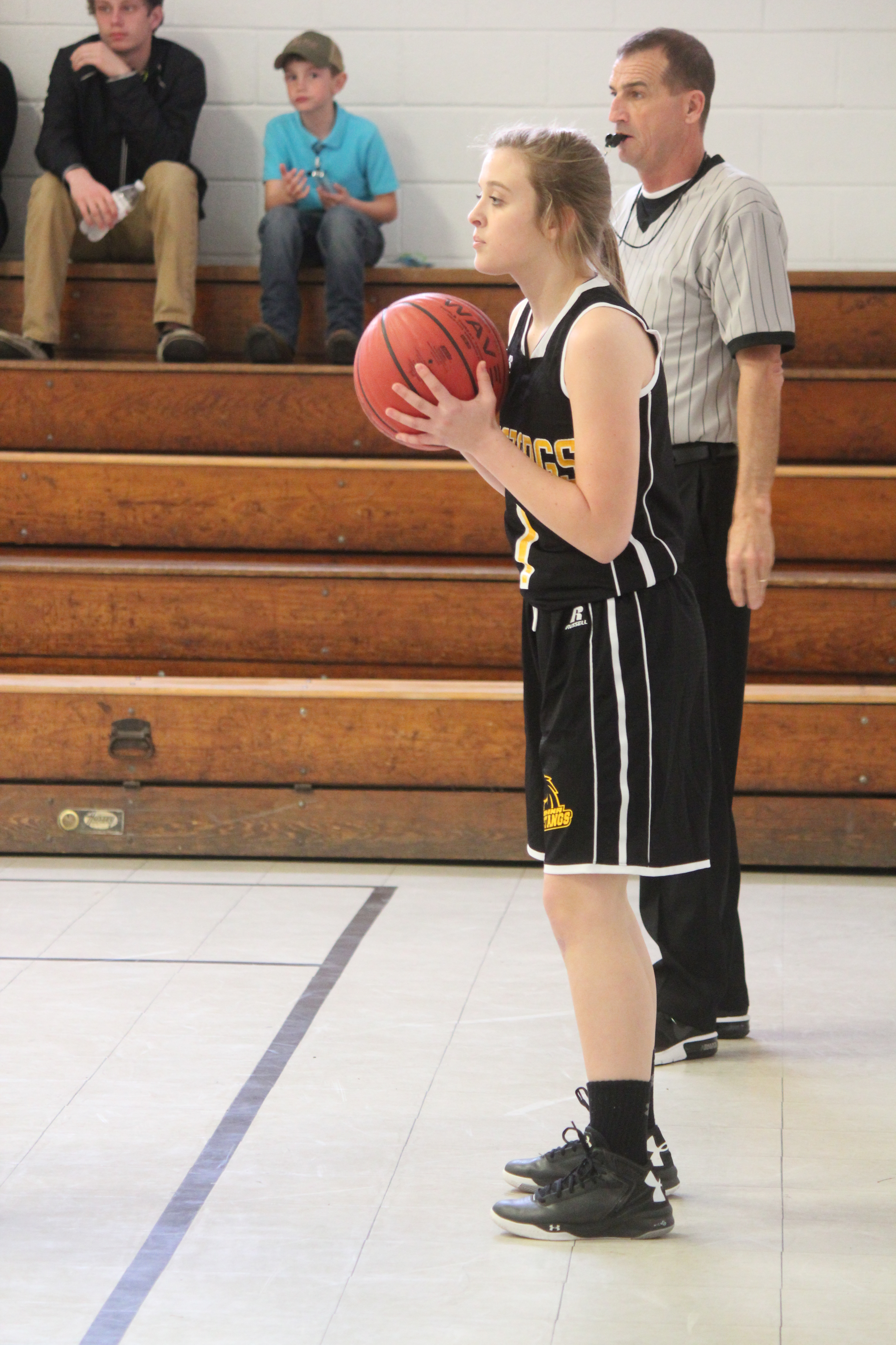 A girl in a black and white uniform holding a basketball.