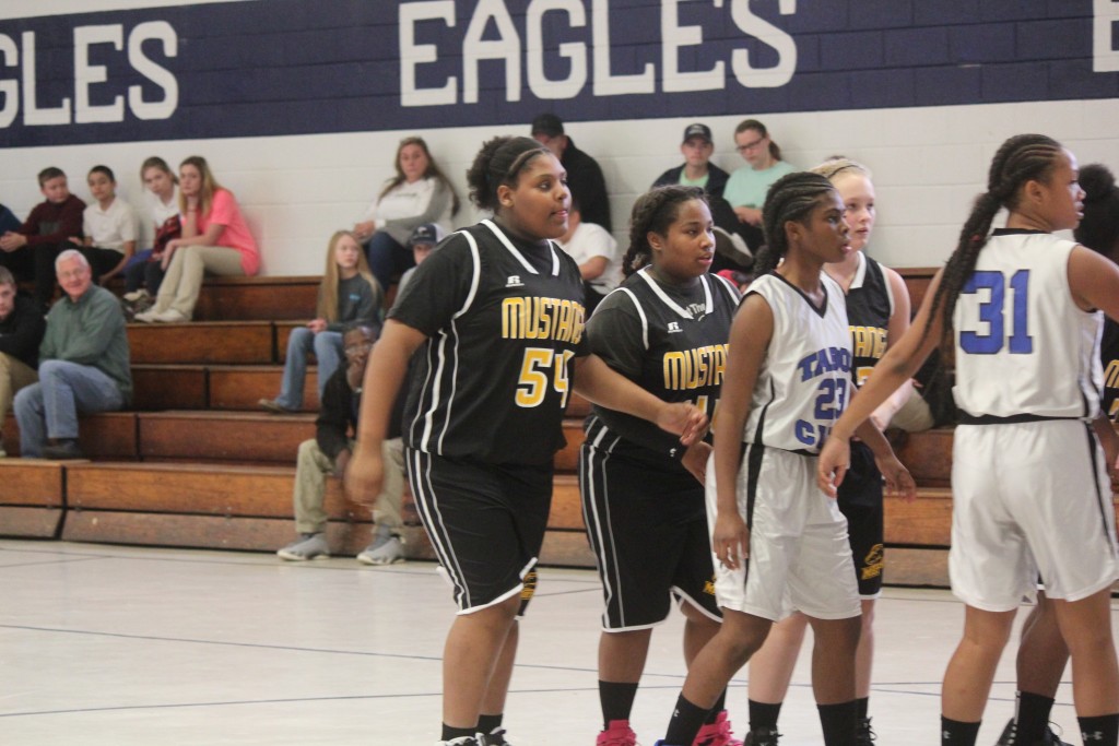 A girls basketball team huddles on the court, strategizing before the game.