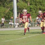 Football player running with ball on field during game.