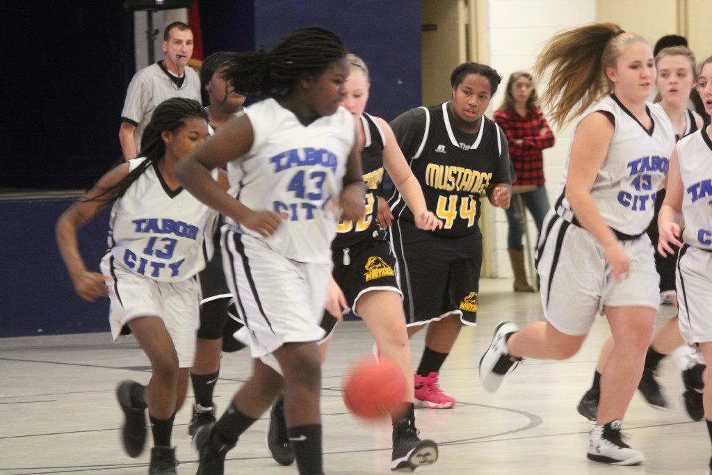 Young female basketball players sprinting down court during intense game.