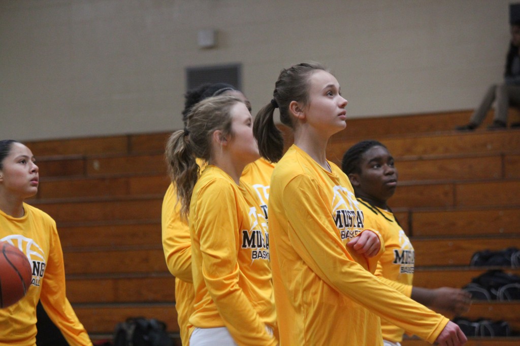 A group of female basketball players in yellow uniforms standing on the court.