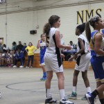 Young female basketball players dribbling and shooting on the court during a game.