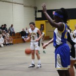 Young female basketball players dribbling and shooting on the court during a game.