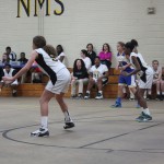 Young female basketball players dribbling and shooting on the court during a game.