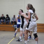 Young female basketball players dribbling and shooting on the court during a game.