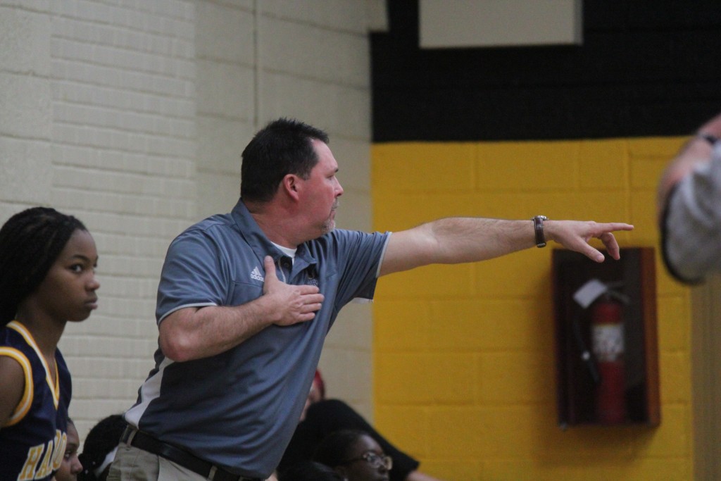 A man pointing to a basketball player on the court.