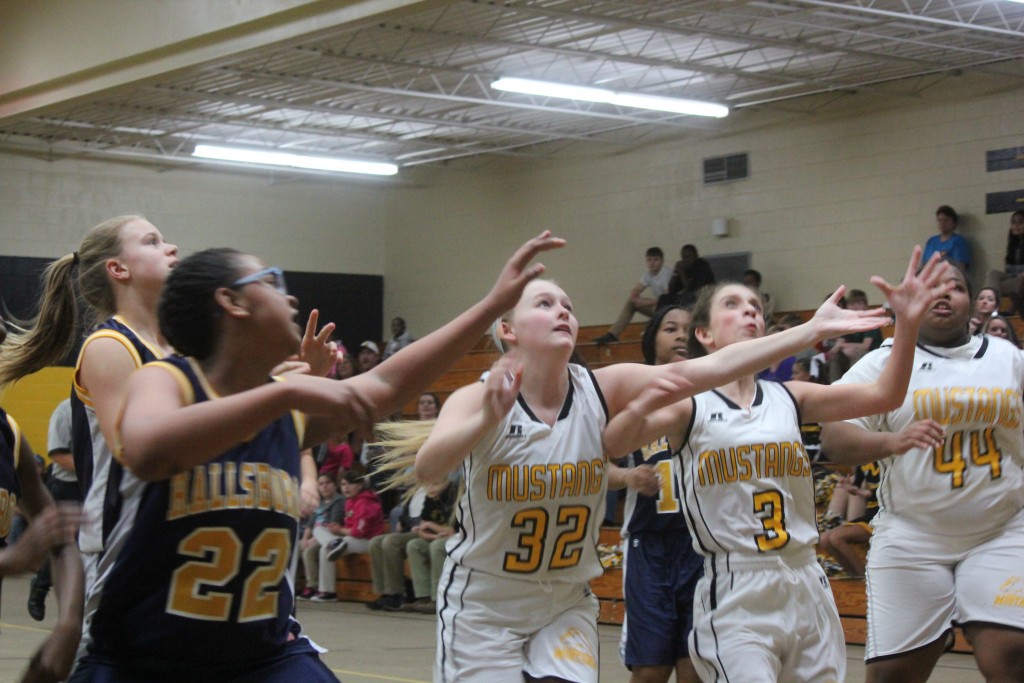 A girls' basketball game in progress with a crowd of spectators in the stands.