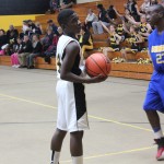 Two young men playing basketball in a gym.