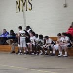 Several boys sitting on a gym bench.