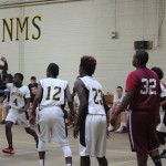 Boys playing basketball in a gymnasium, dribbling and shooting hoops.