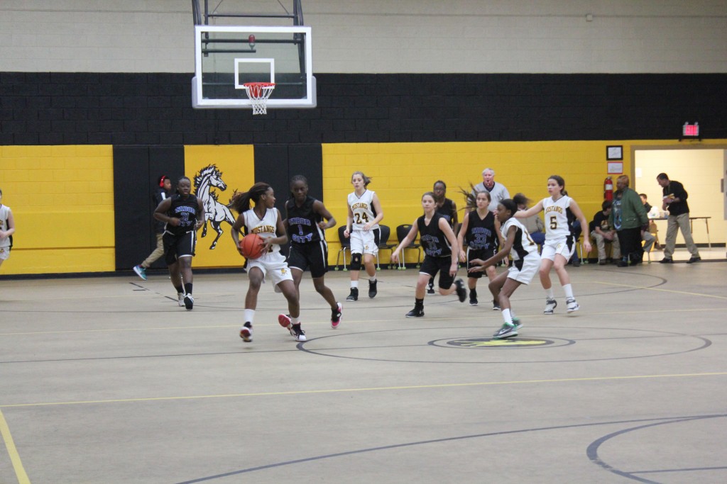 Girls basketball team playing in gymnasium.