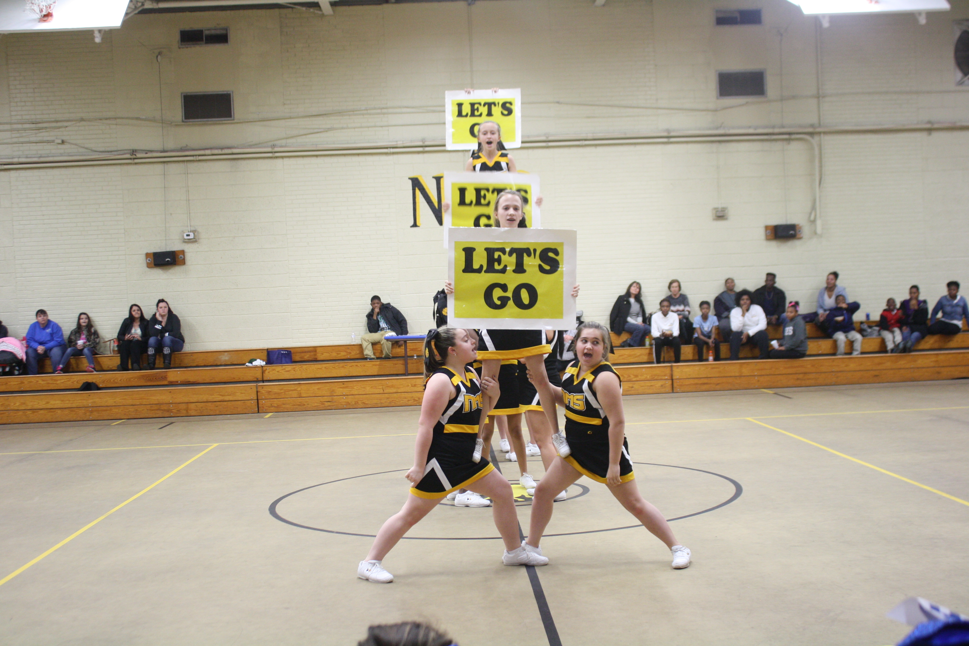 Cheerleaders in uniform perform energetic routine at school pep rally.