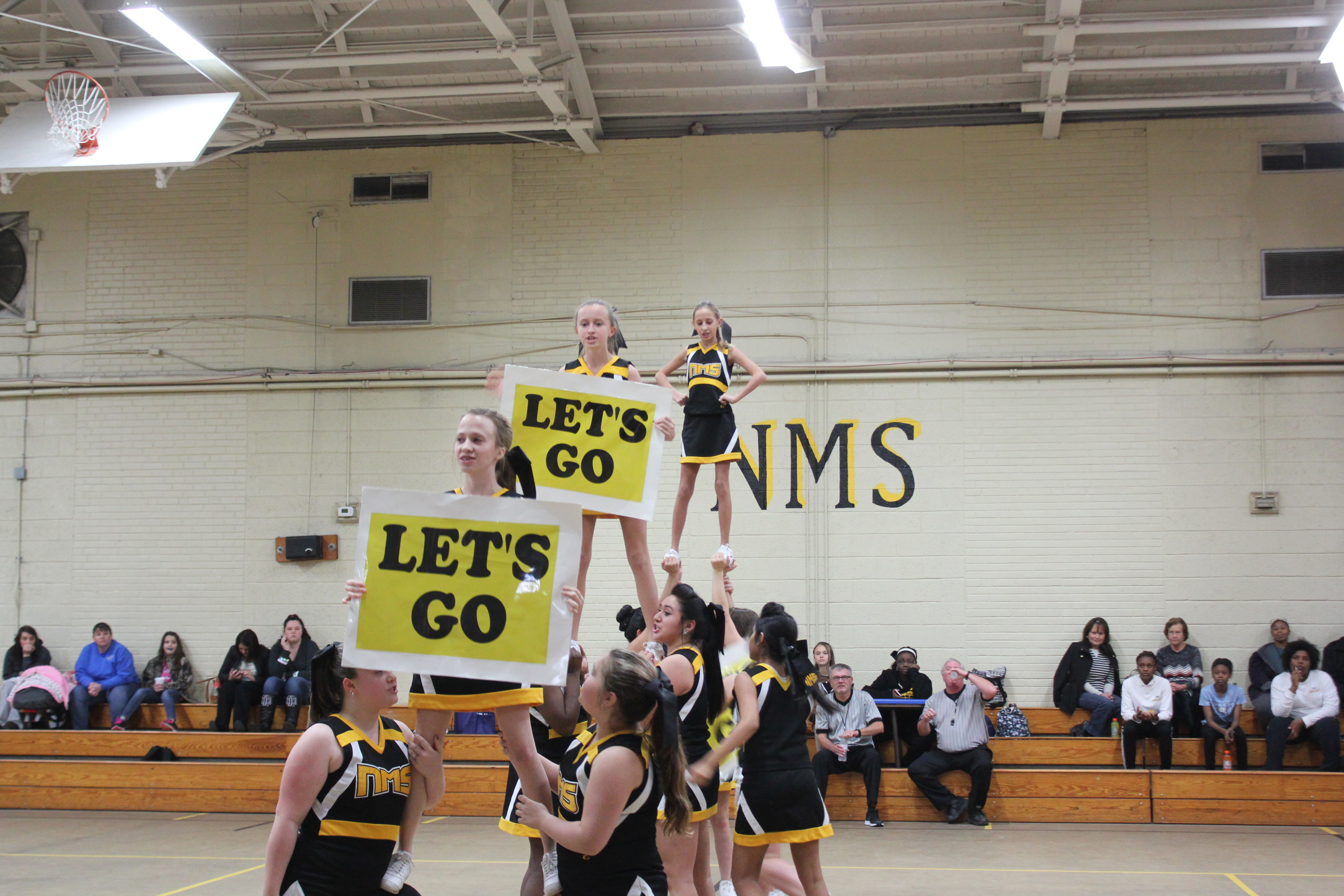 Cheerleaders in uniform perform energetic routine at school pep rally.