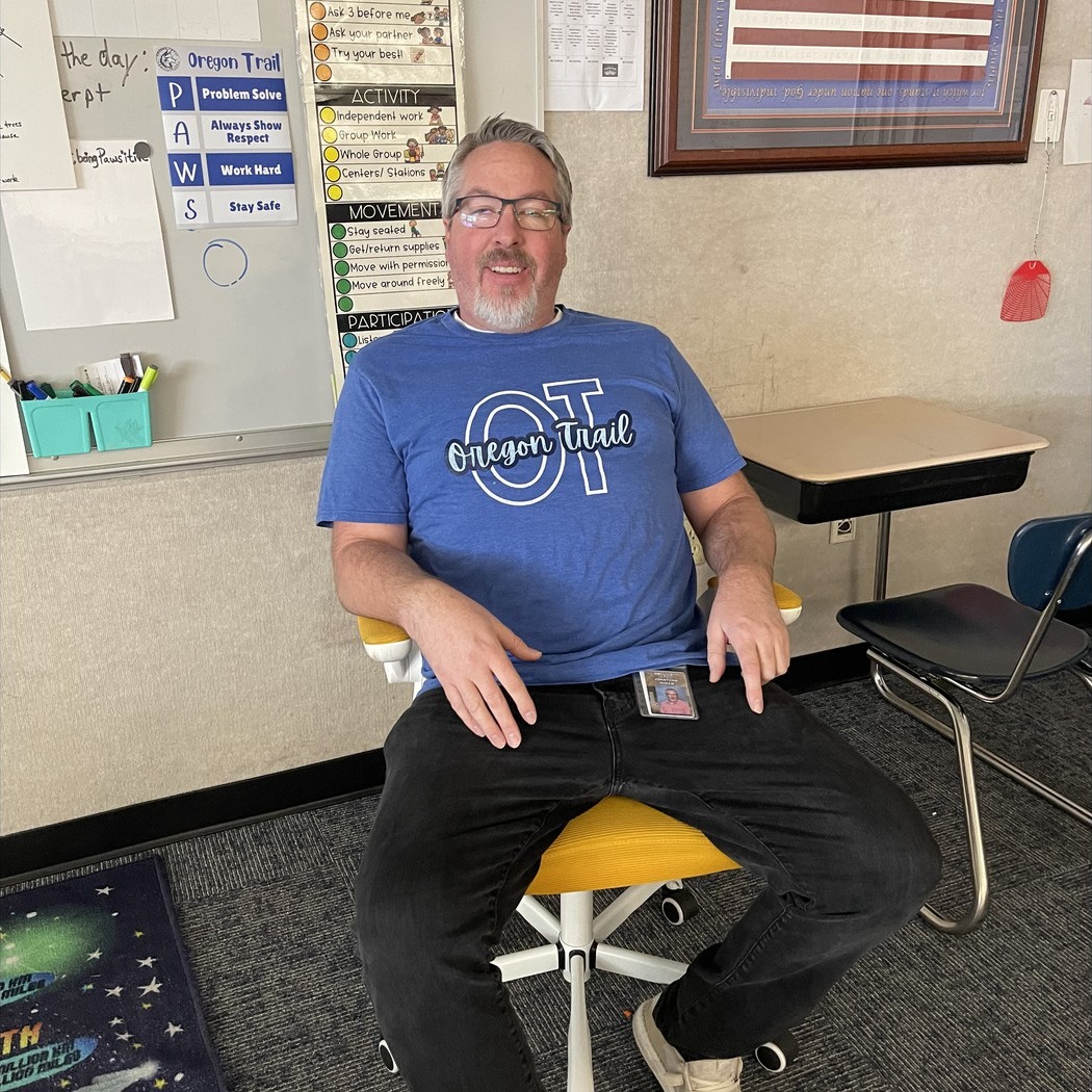 Teacher sitting in golden chair posing.