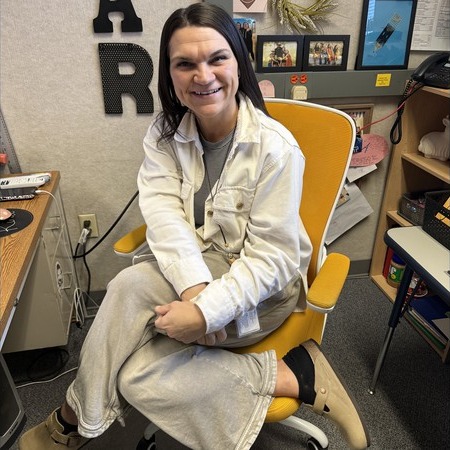 Teacher sitting in golden chair posing.