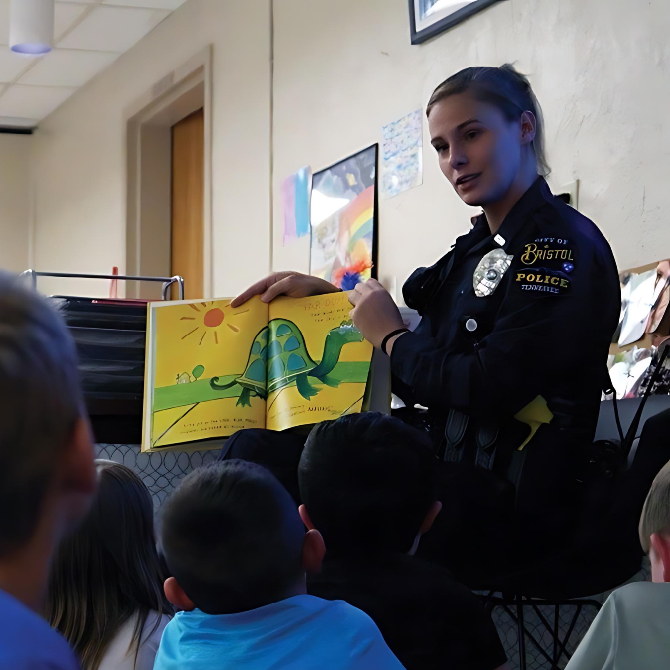 Photo of School Resource Officer reading a book to elementary students