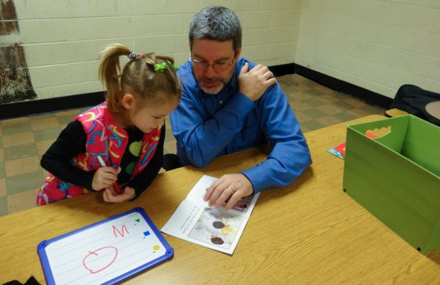 parent helping kid read a book