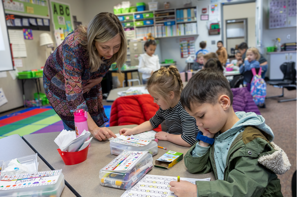 Teacher works with students in a primary classroom