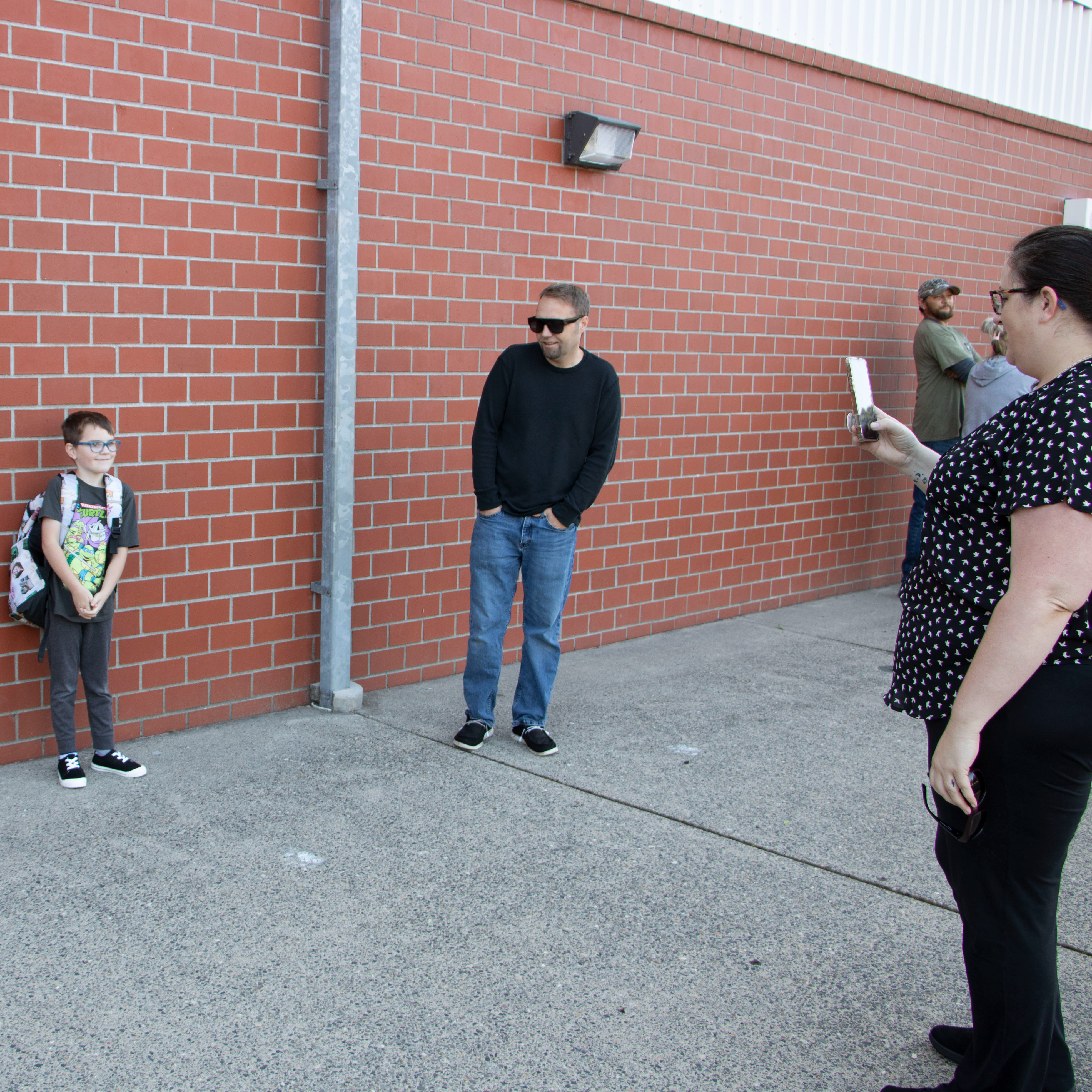 A parent takes a first day of school photo of a student