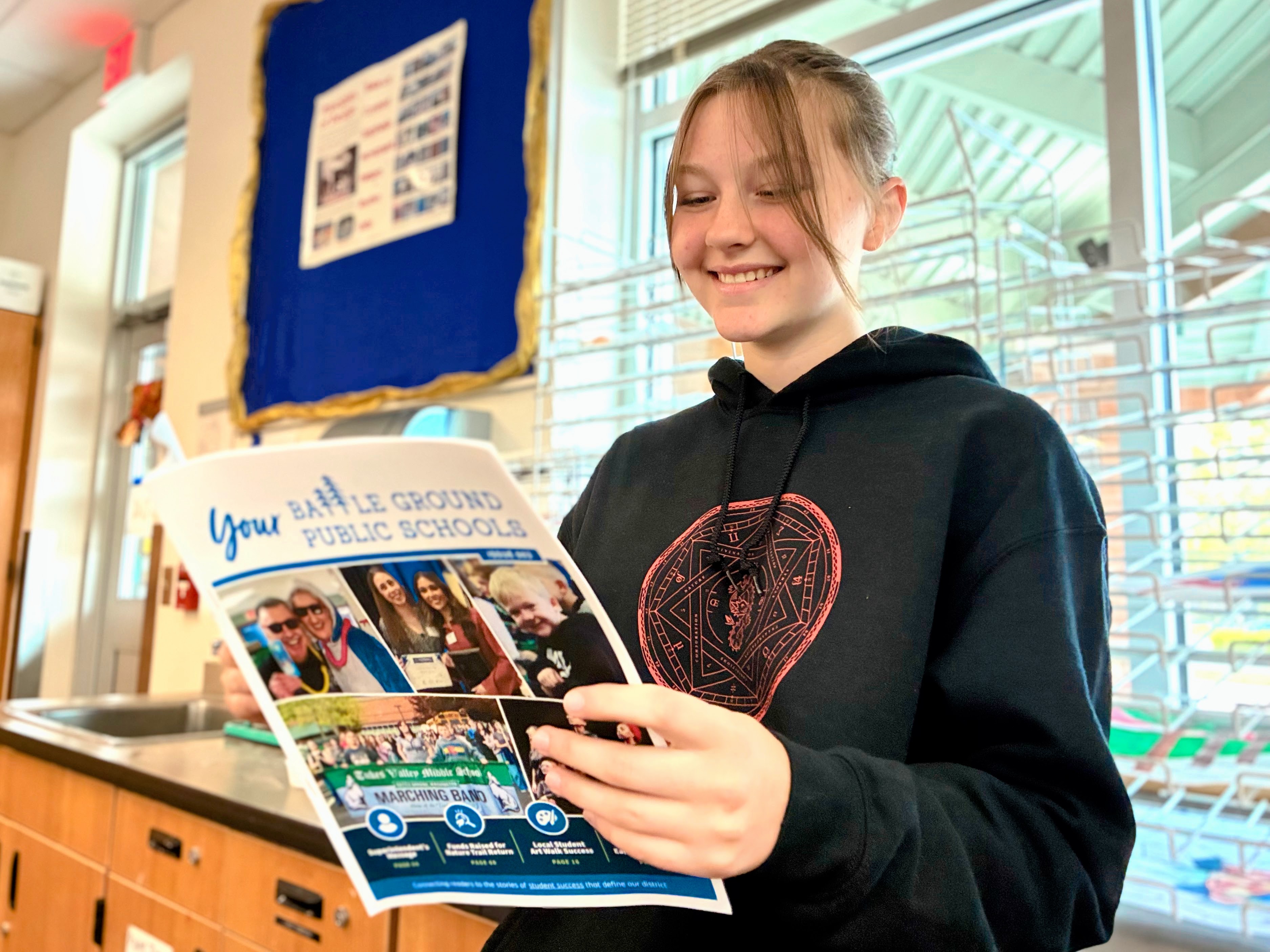 a student smiles while reading a student publication