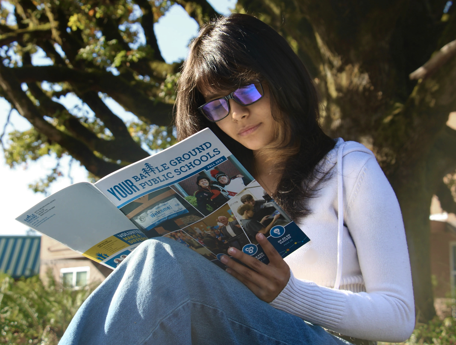 a student smiles while reading a student publication