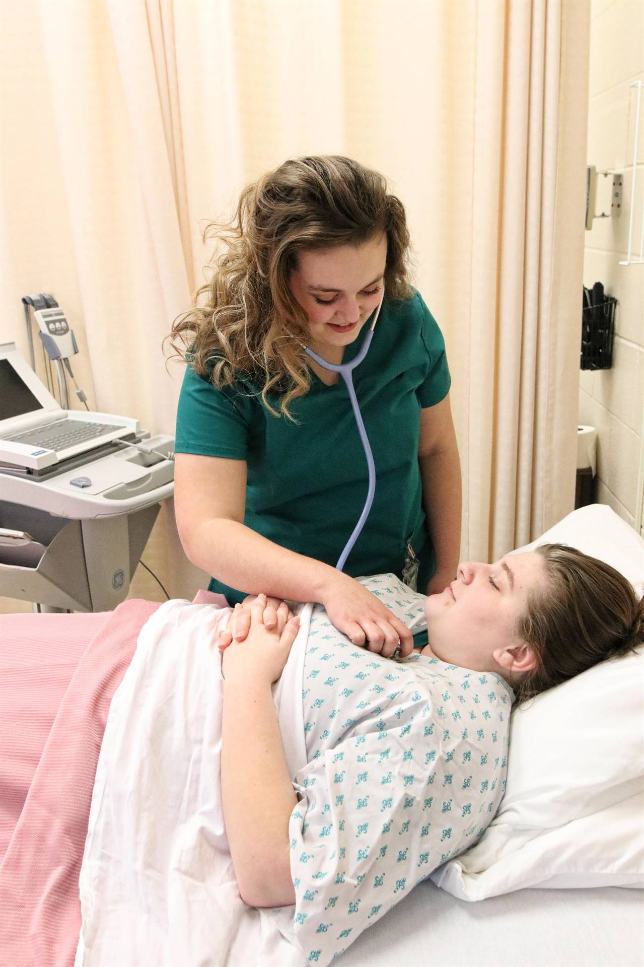 nurse checking the pulse on a woman laying down