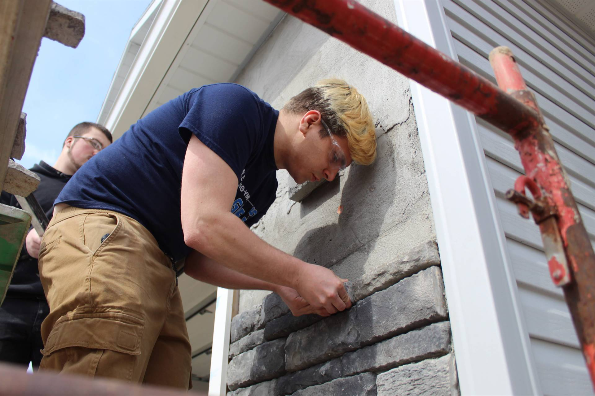 man fixing a brick on a wall