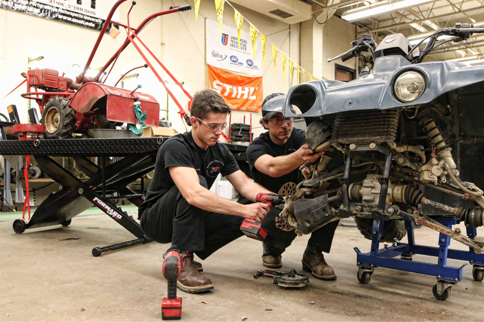 2 guys working on an old car with tools