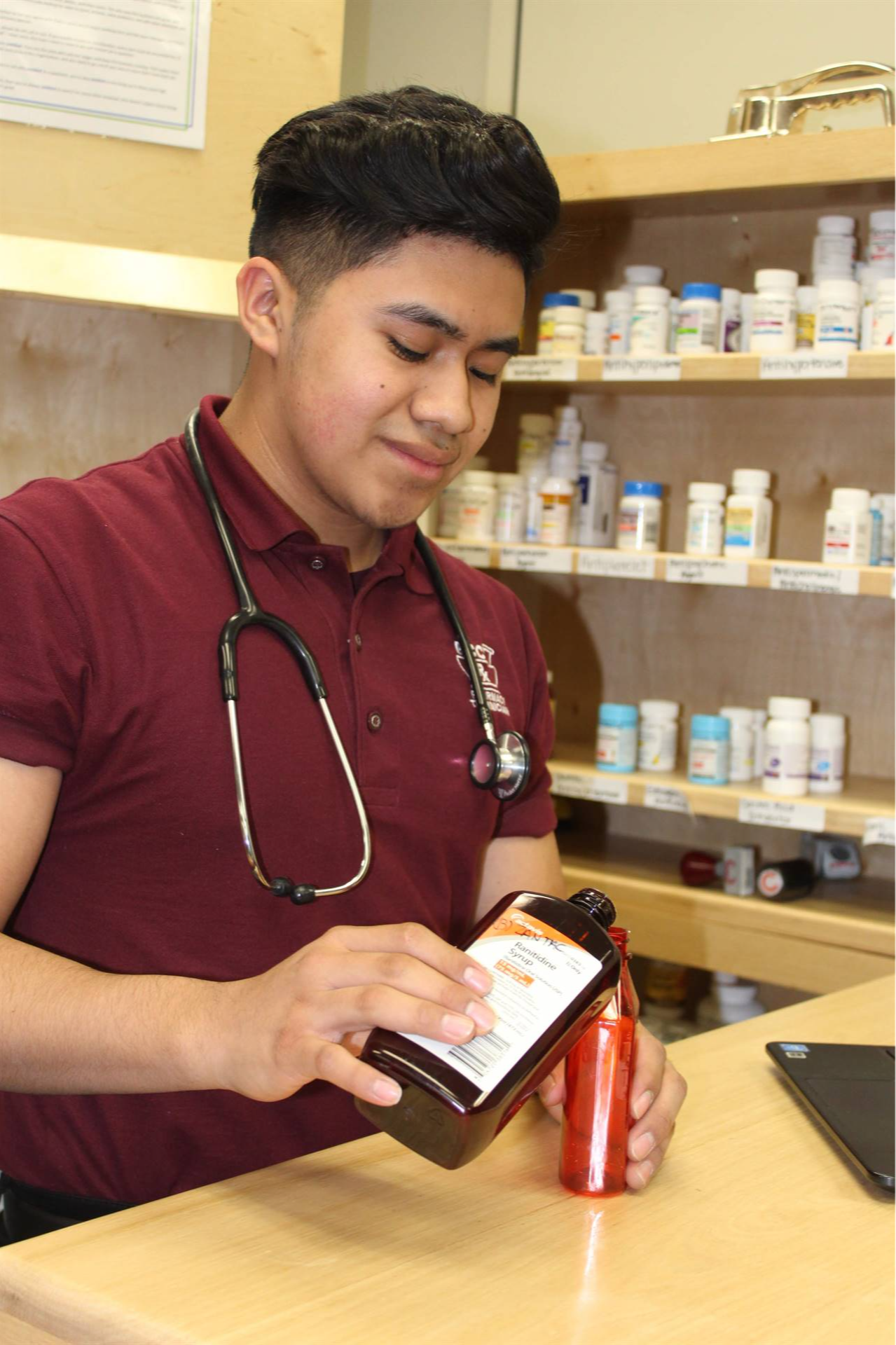 guy working on the pharmacy pouring medicine in a bottle