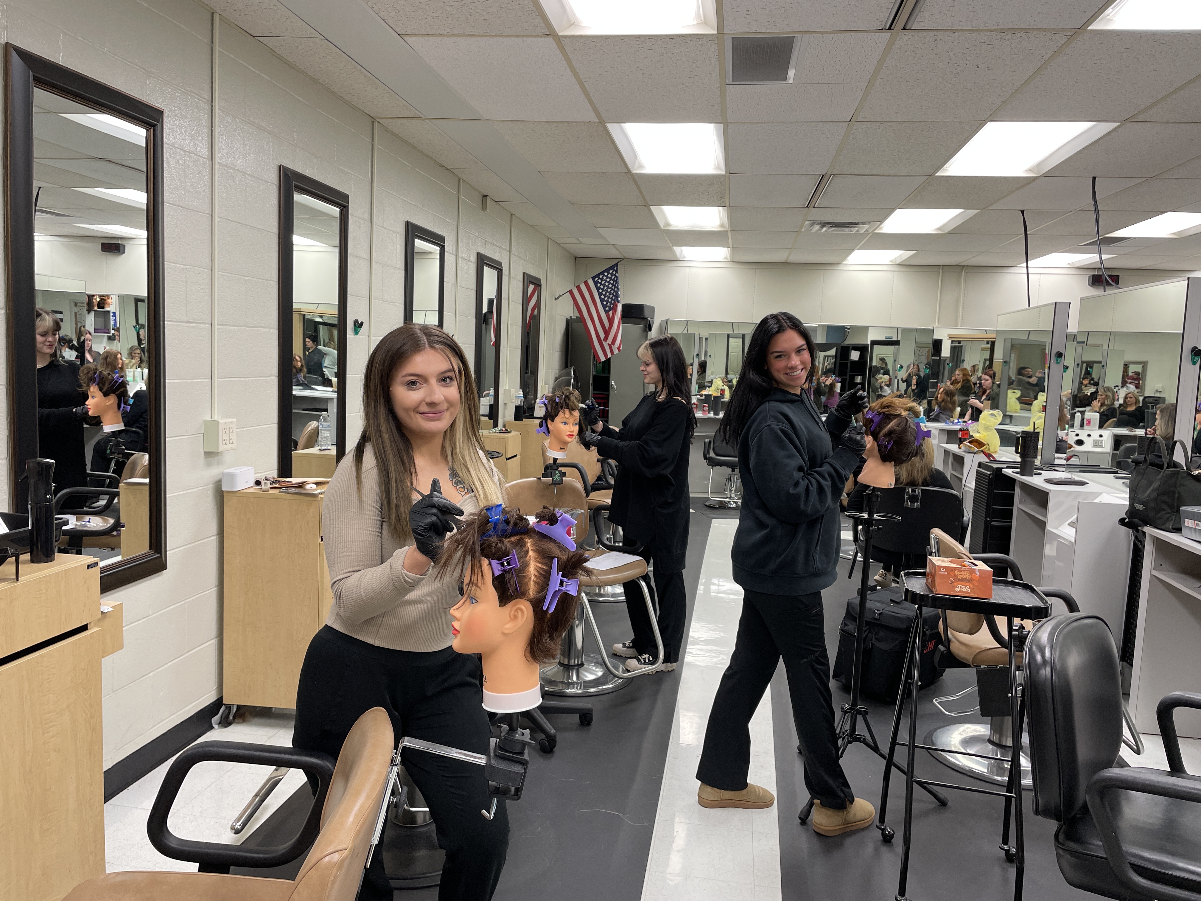 adult students in cosmetology applying color to  mannequin heads