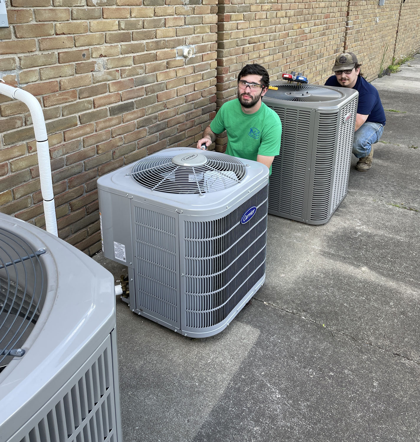 2 males students working on an outside air conditioning unit