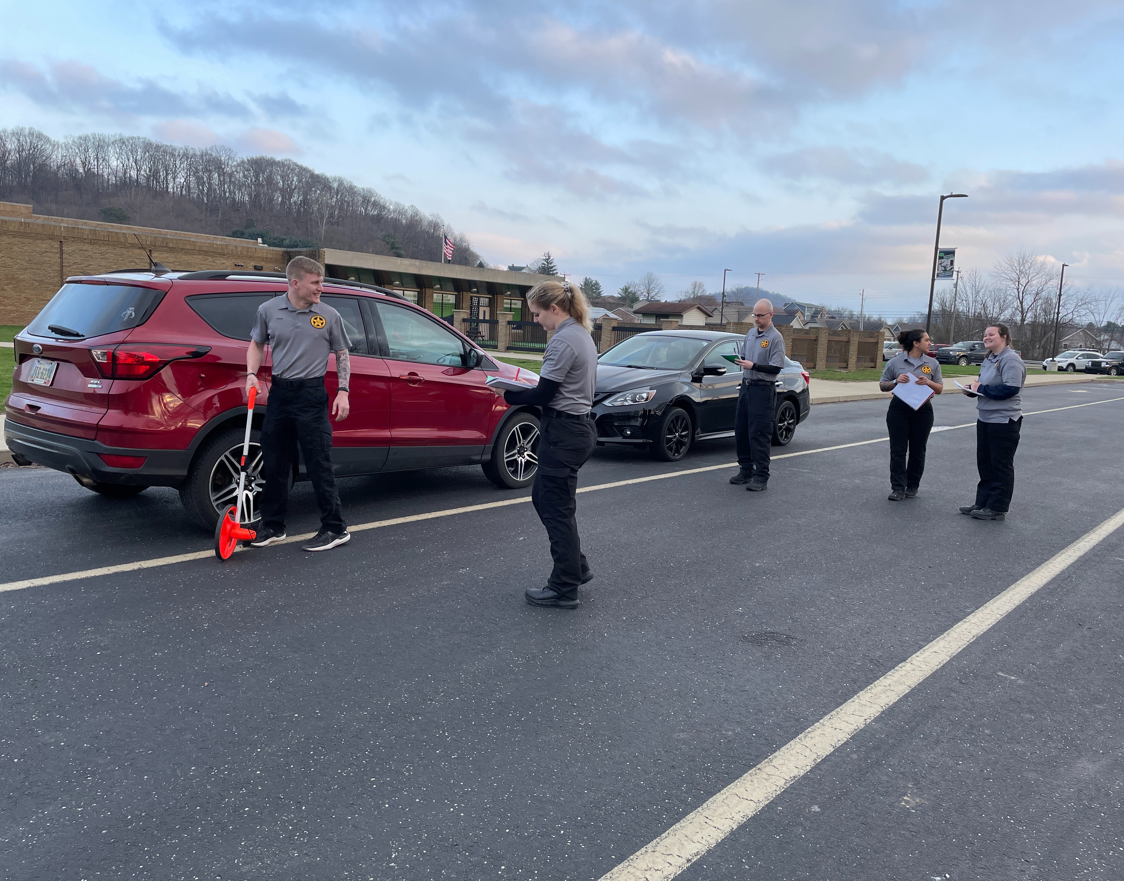 students practicing a traffic stop with a red vehicle, measuring and recording information