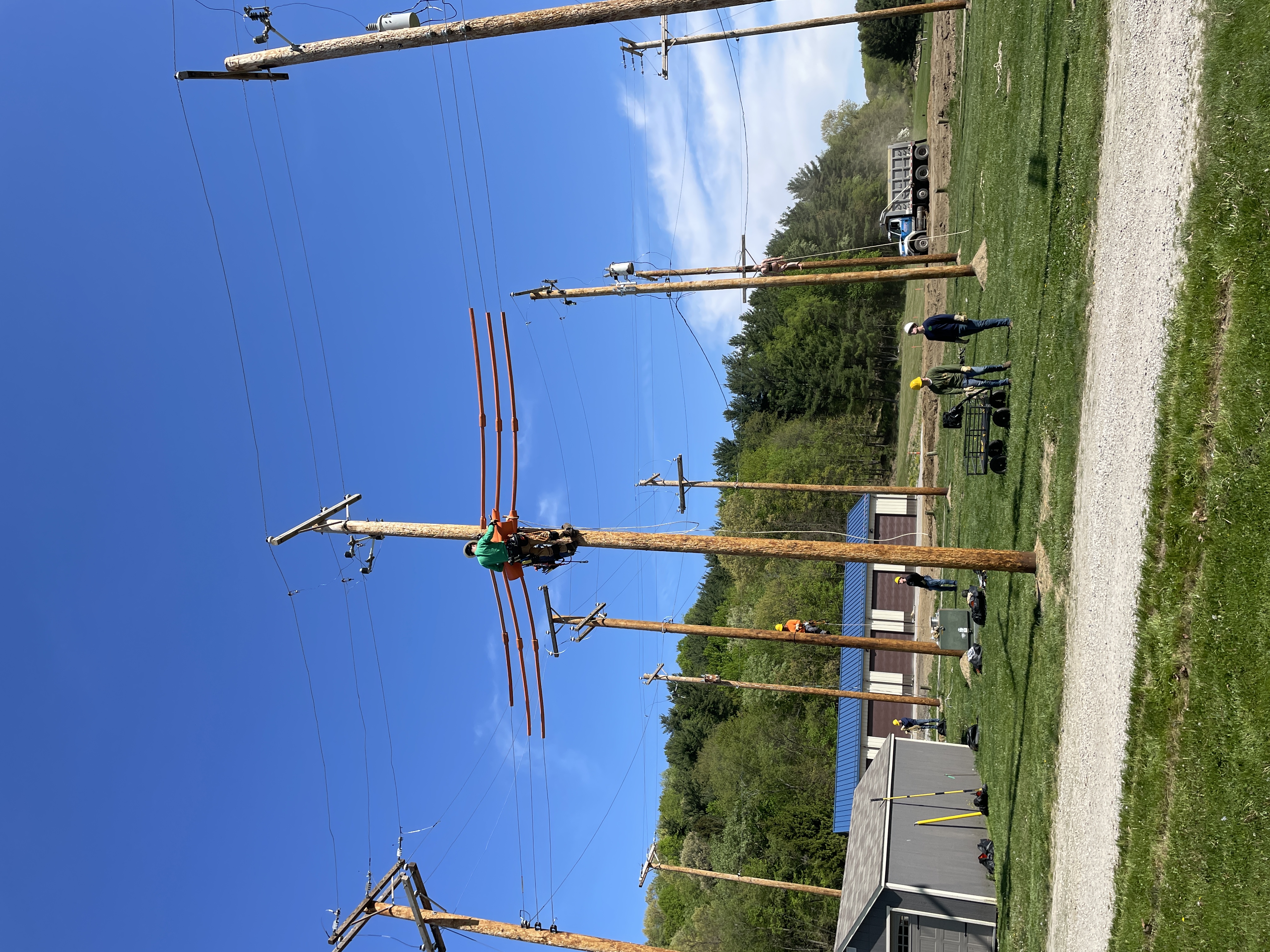 student climbing a utility pole with others looking on from the ground