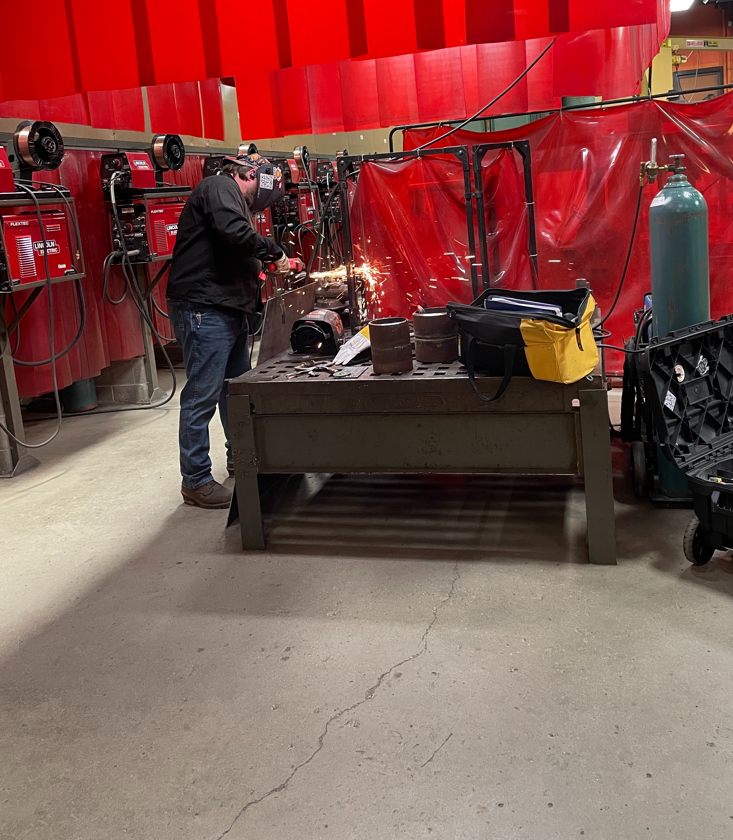 male student welding outside the booth on a welding table