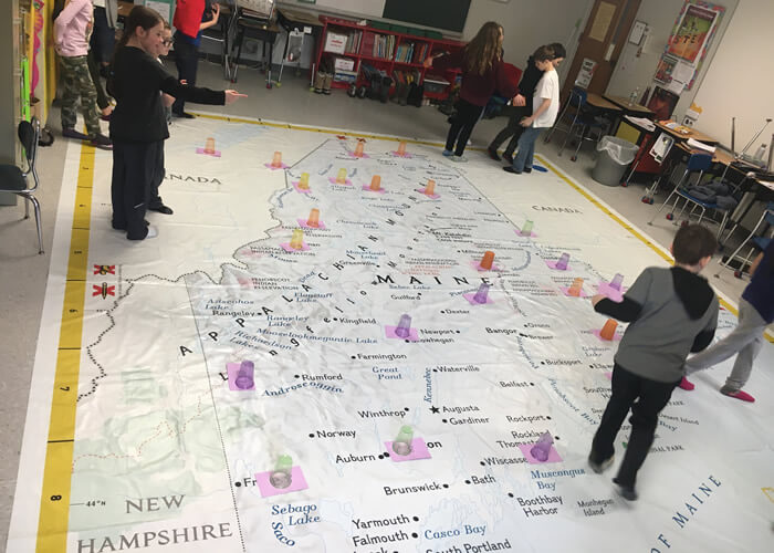 Students with floor size map of Maine