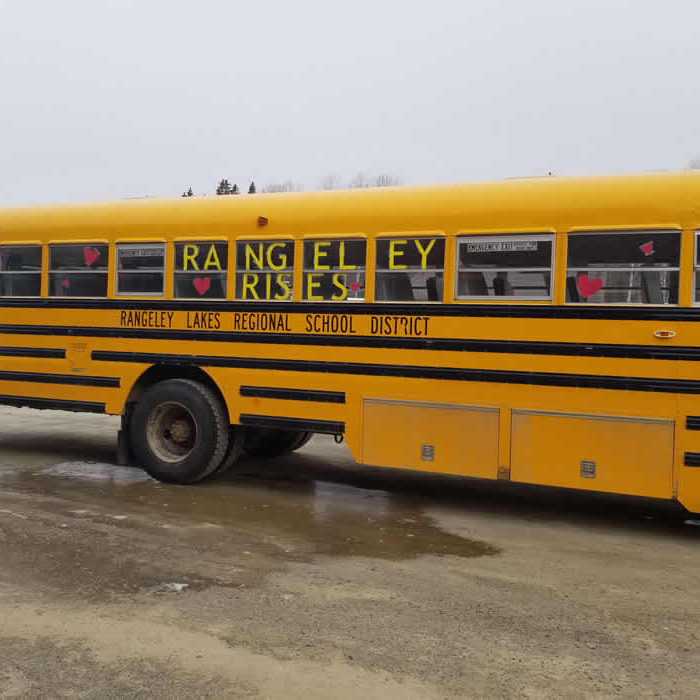 a schoolbus with "Rangeley Rises" taped inside of the windows