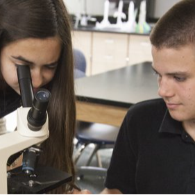 two students looking through a microscope